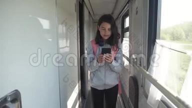十几岁的女孩带着背包和智能手机在<strong>火车车厢</strong>里散步。 旅行交通方式铁路