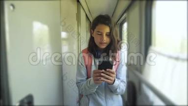 十几岁的女孩带着背包和智能手机在<strong>火车车厢</strong>里散步。 旅游运输铁路概念。 这就是