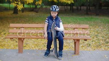 一个手臂骨折的白人男孩坐在溜冰场