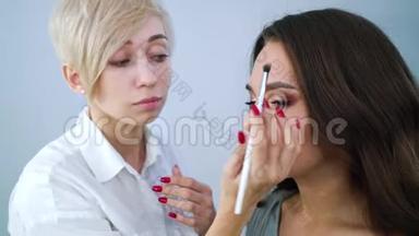 美妆师在美容院用画笔将化妆品涂在美女脸上