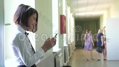 在学校概念上使用智能手机的女学生教育。 年轻女孩和使用智能手机站在生活方式旁边
