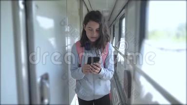 十几岁的女孩走在火车车厢里，带着生活方式、背包和智能手机。 交通运输
