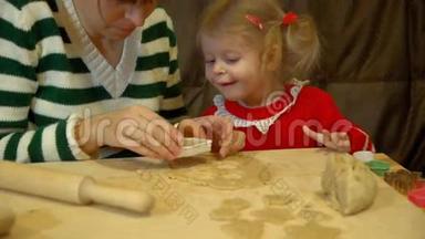 女人和蹒跚学步的女孩为家庭圣诞夜晚餐准备姜饼。