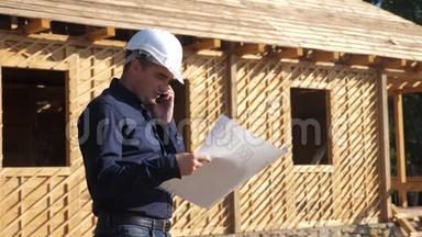 概念建筑构建建筑师慢动作视频.. 戴着头盔的建筑工人站在一座建筑上，手持一个