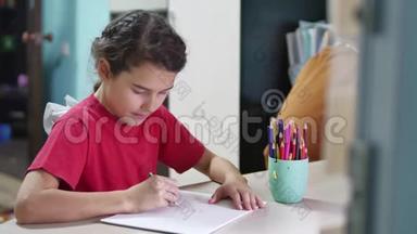 小女孩在桌子上画画。 女学生青少年在室内用铅笔画画