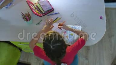 小女孩在桌子上画画。 女学生青少年在室内用铅笔画画
