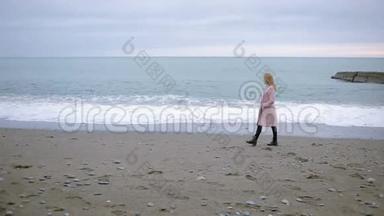 暴风雨时，穿着粉红色外套的快乐女孩在海边。 大风。