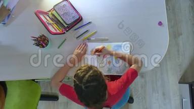 小女孩在油漆桌上画画。 女学生青少年在室内用铅笔画画