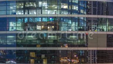 多层现代玻璃和金属<strong>办公楼</strong>中的发光窗在<strong>夜晚</strong>时光倒流时点亮。