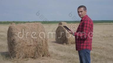 智慧农业理念.. 一名农<strong>民工</strong>人在数字平板电脑上的田野里研究干草堆。 慢速视频
