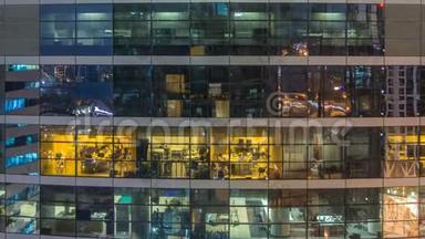 多层现代玻璃和金属办公楼中的发光窗在夜晚<strong>时光倒流</strong>时点亮。
