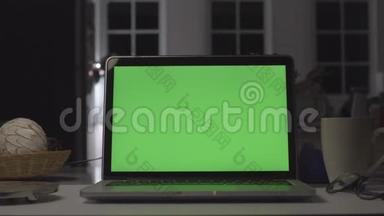 带有绿色屏幕的笔记本电脑。 黑暗的办公室。 完美地放置你自己的图像或视频。