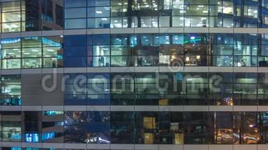 多层现代玻璃和金属办公楼中的发光窗在夜晚时光倒流时点亮。