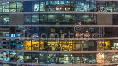 多层现代玻璃和金属办公楼中的发光窗在夜晚<strong>时光倒流</strong>时点亮。