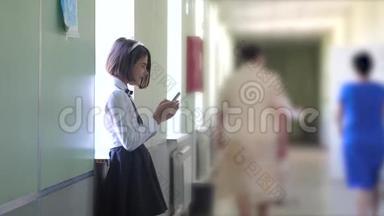 女学生教育与生活方式智能手机在学校的概念。 十几岁的少女和使用智能手机站在旁边