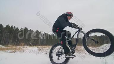 专业的极限运动员骑自行车在户外骑胖自行车。 骑自行车在冬天的雪林里。 男人是审判