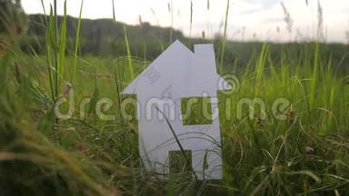 幸福家庭建设生活方式之家理念.. 纸屋矗立在大自然的绿草中。 象征生命生态