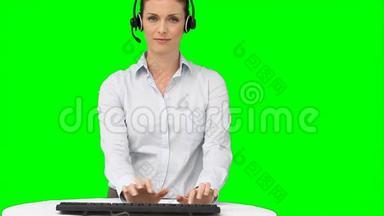 一个拿着耳机在<strong>键盘</strong>上打字的女人