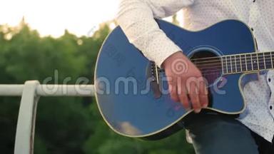 男人弹吉他。 吉他手在触摸吉他弦。 近距离射击。