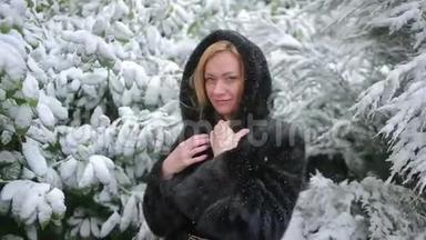 穿着时髦<strong>貂皮</strong>大衣的年轻美女在冬季公园的背景下