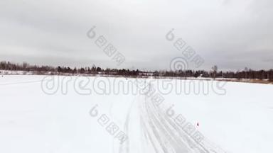冬天，在雪覆盖的湖面上，汽车在结冰的轨道上行驶。 空中观景。 冬季雪地赛道上的赛车