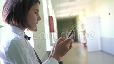 生活方式女学生教育与智能手机在学校的概念。 十几岁的少女和使用智能手机站在旁边