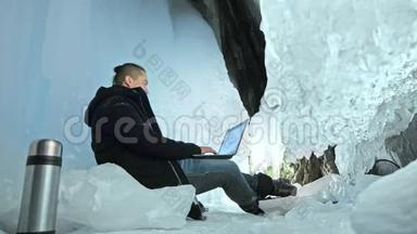 人们坐在冰洞里的笔记本电脑上。 围绕着神秘美丽的冰窟.. 用户在