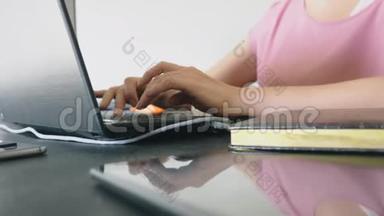 坐在办公桌前工作在笔记本电脑上的女人。