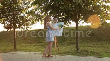 美丽的女孩在公园里画一幅画，用颜料和铲子调<strong>色板</strong>。 带有<strong>图片</strong>的简易帆布
