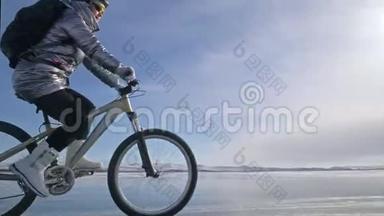 女人在冰上骑自行车。 女孩穿着银色<strong>羽绒服</strong>，自行车背包和头盔。 冰冰