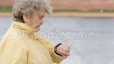 老妇人看着<strong>腕带</strong>健身追踪器