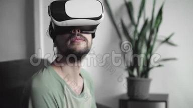 年轻留胡子的嬉皮士用他的VR耳机显示虚拟现实游戏或观看360视频坐着