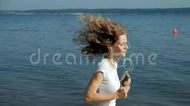 一个<strong>身材好</strong>的年轻女子在黎明时在海里从事体操。 她戴着耳机沿着海岸跑