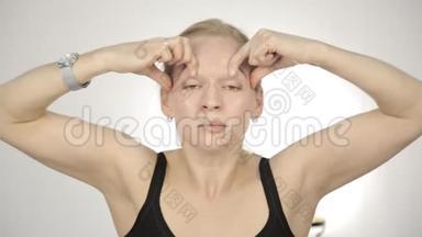 金发女人在办公室做自我按摩，抗衰老面部按摩。 日常面部健身和面部建设。