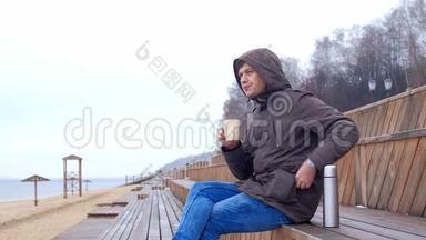 浪漫的年轻人在海滩上放松，<strong>喝</strong>热茶或<strong>热水</strong>瓶咖啡。 平静舒适的夜晚。