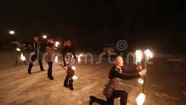 令人惊叹的部落火秀在夜幕下的冬天跳舞。 舞蹈团用火炬灯表演