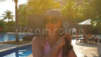 游泳池边戴蓝帽子的漂亮女孩。 夏日阳光