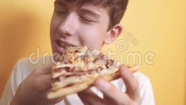 快乐的小男孩吃一片披萨的概念。 少年男孩饿了吃一片披萨。 慢动作视频。 比萨饼快