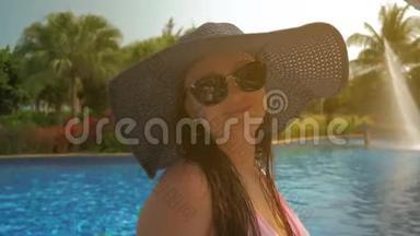 游泳池边戴蓝帽子的漂亮女孩。 夏日阳光