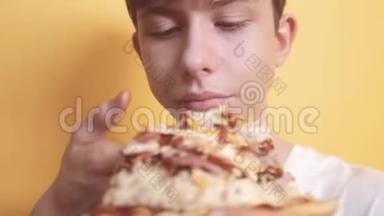 披萨。快乐少年男孩吃比萨饼的概念。饥饿的十几岁男孩吃了一片比萨饼。慢动作视频
