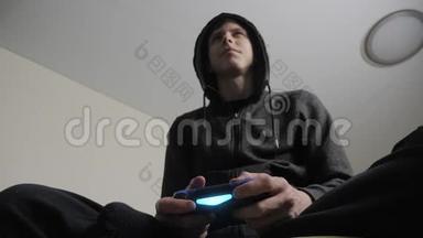 男孩少年在引擎盖上玩电子游戏的控制台上的游戏。 青少年穿着头罩毛衣