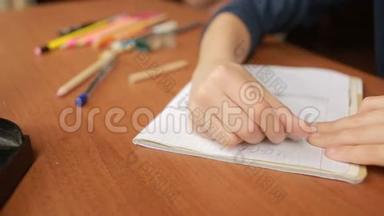 一个青少年在笔记本上画一支简单的铅笔。 特写