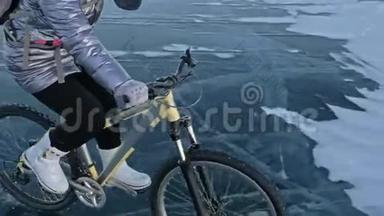 女人在冰上骑自行车。 女孩穿着银色<strong>羽绒服</strong>，自行车背包和头盔。 冰冰