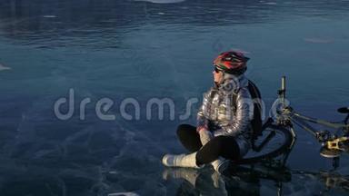 女人在冰上骑自行车。 女孩穿着银色<strong>羽绒服</strong>，自行车背包和头盔。 这就是