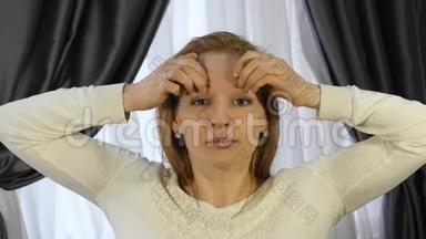 金发女人在办公室做自我按摩，抗衰老面部按摩。 日常面部健身和面部建设。
