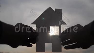 <strong>幸福家园</strong>建设理念.. 在夕阳的余晖下，一个人手里拿着一个纸房子。 生活