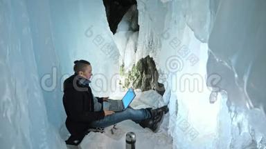 人们坐在冰洞里的笔记本电脑上。 围绕着神秘美丽的冰窟.. 用户在