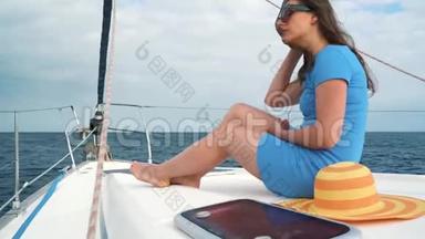 穿着黄色帽子和蓝色衣服的女人在海洋的夏季在游艇上休息