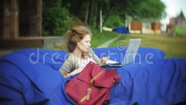 年轻女子用手提电脑，躺在公园的一个<strong>休息区</strong>，软泡芙上