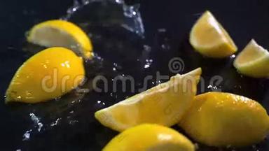 缓慢运动的柠檬在黑色表面上<strong>落下水滴</strong>。